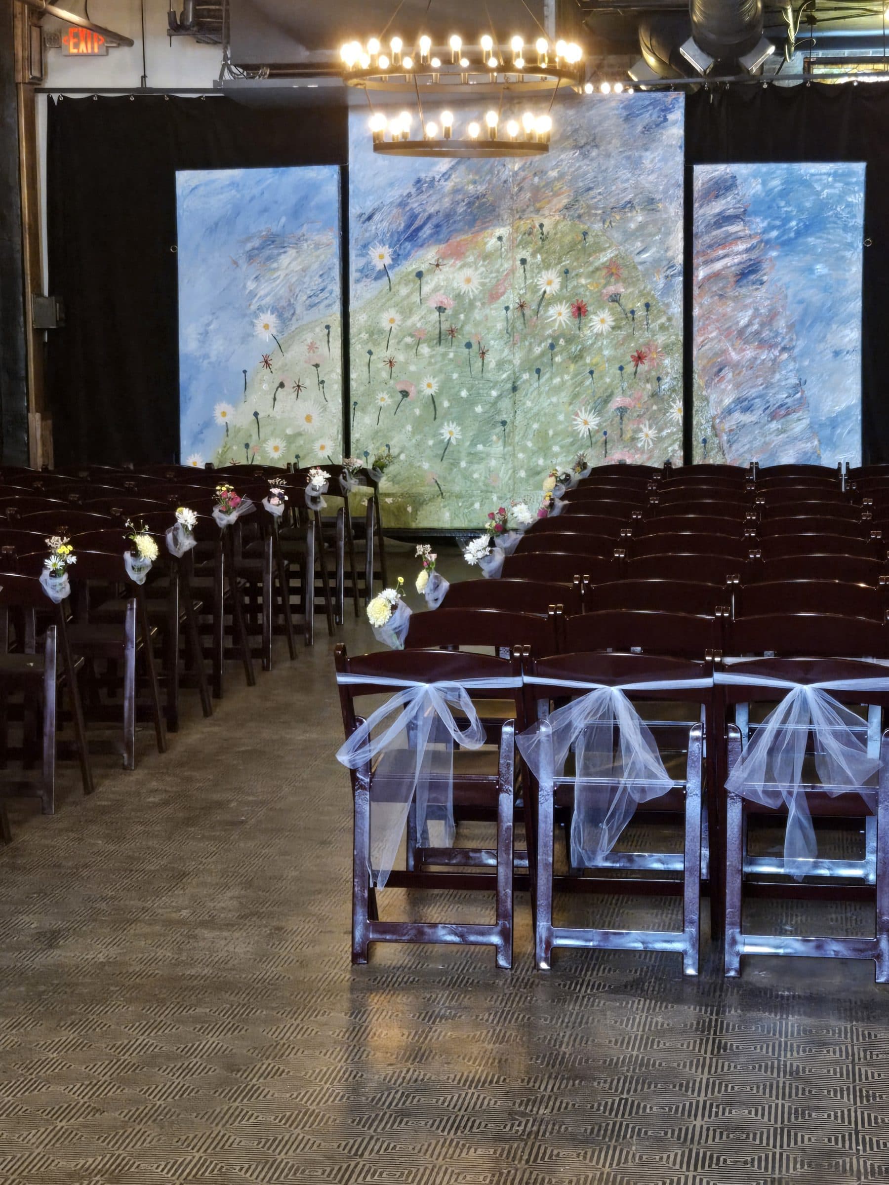 Ceremony set up with rows of chairs facing an original artwork backdrop
