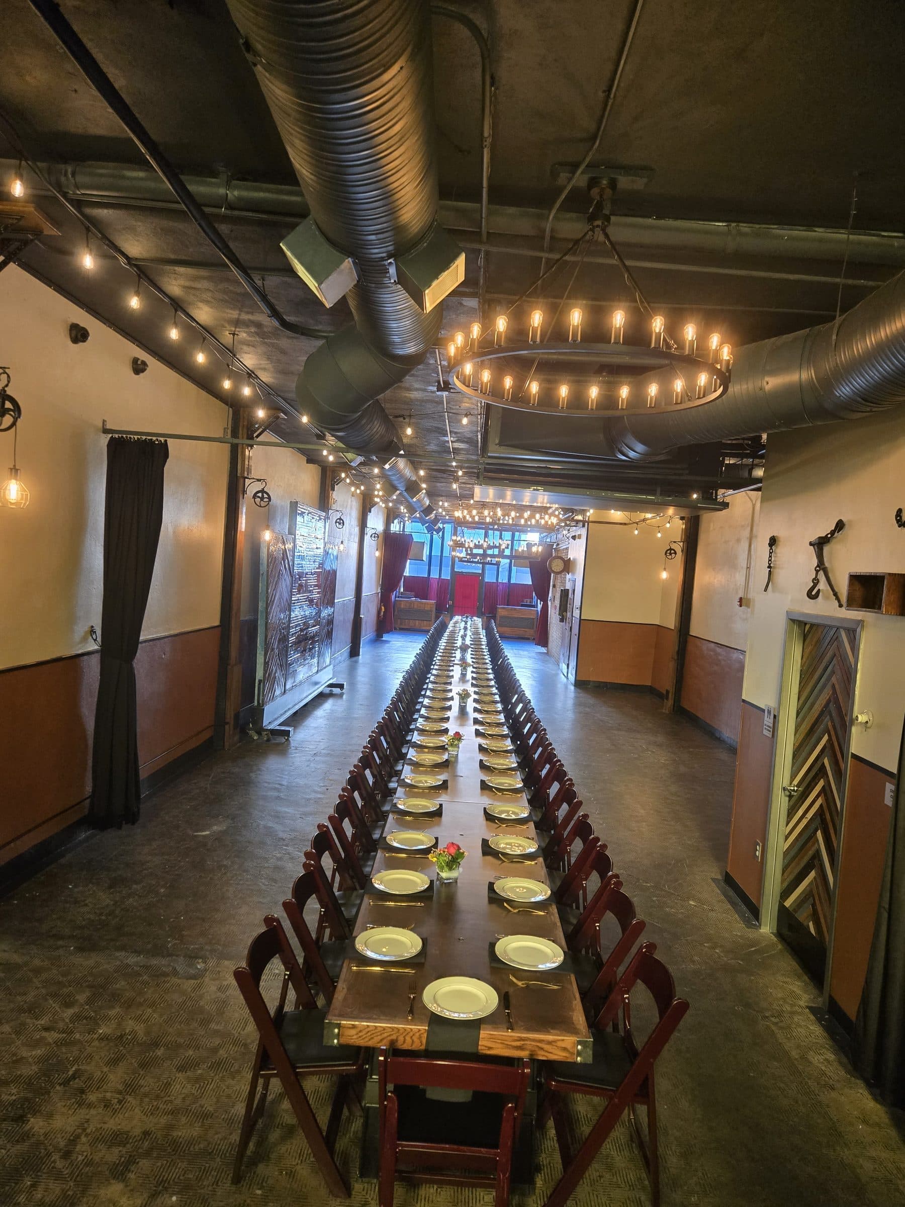 Banquet table running the length of the hall under string-light chandeliers