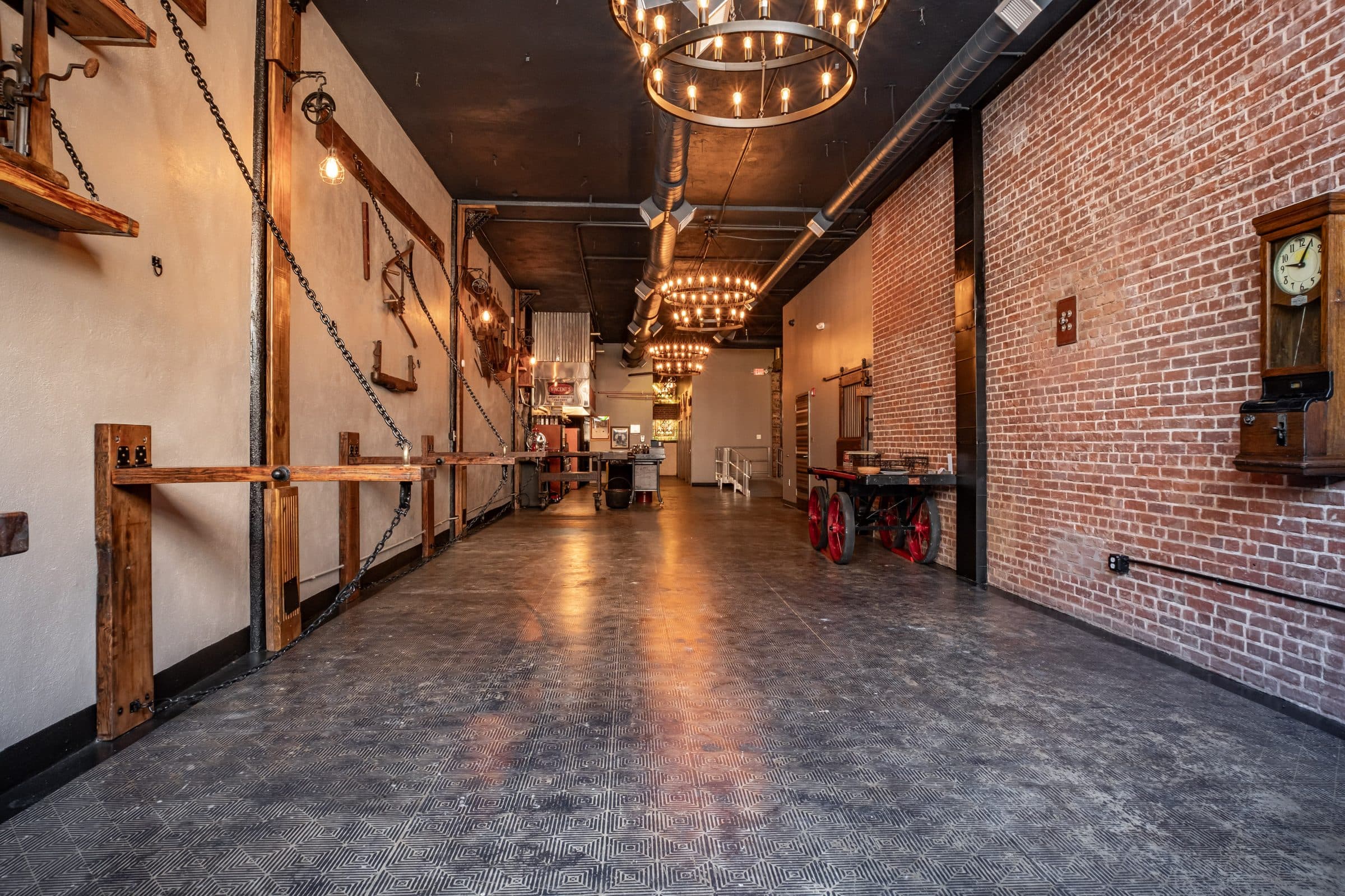 Length of the hall with exposed brick, ring chandeliers and stenciled concrete floor