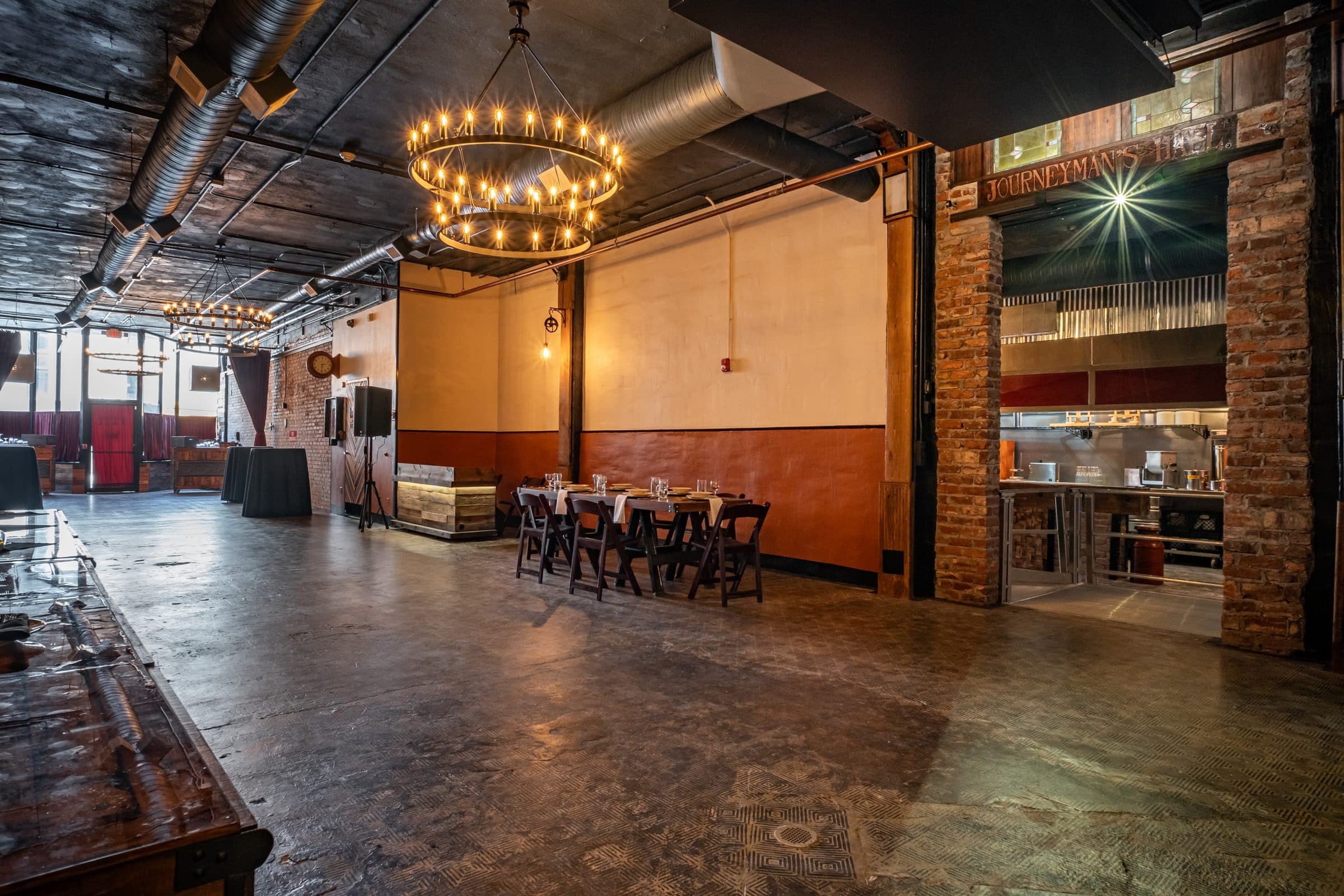 Main hall with dining tables, industrial ductwork and a ring chandelier