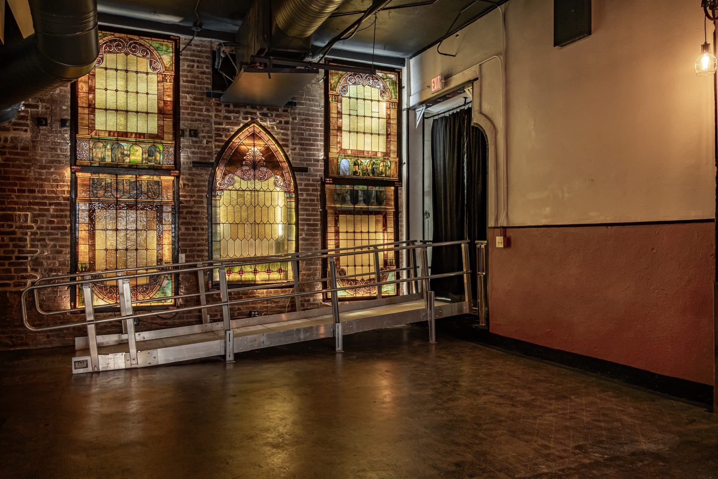 Wide view of the stained-glass wall, brick and concrete floors in the main event hall