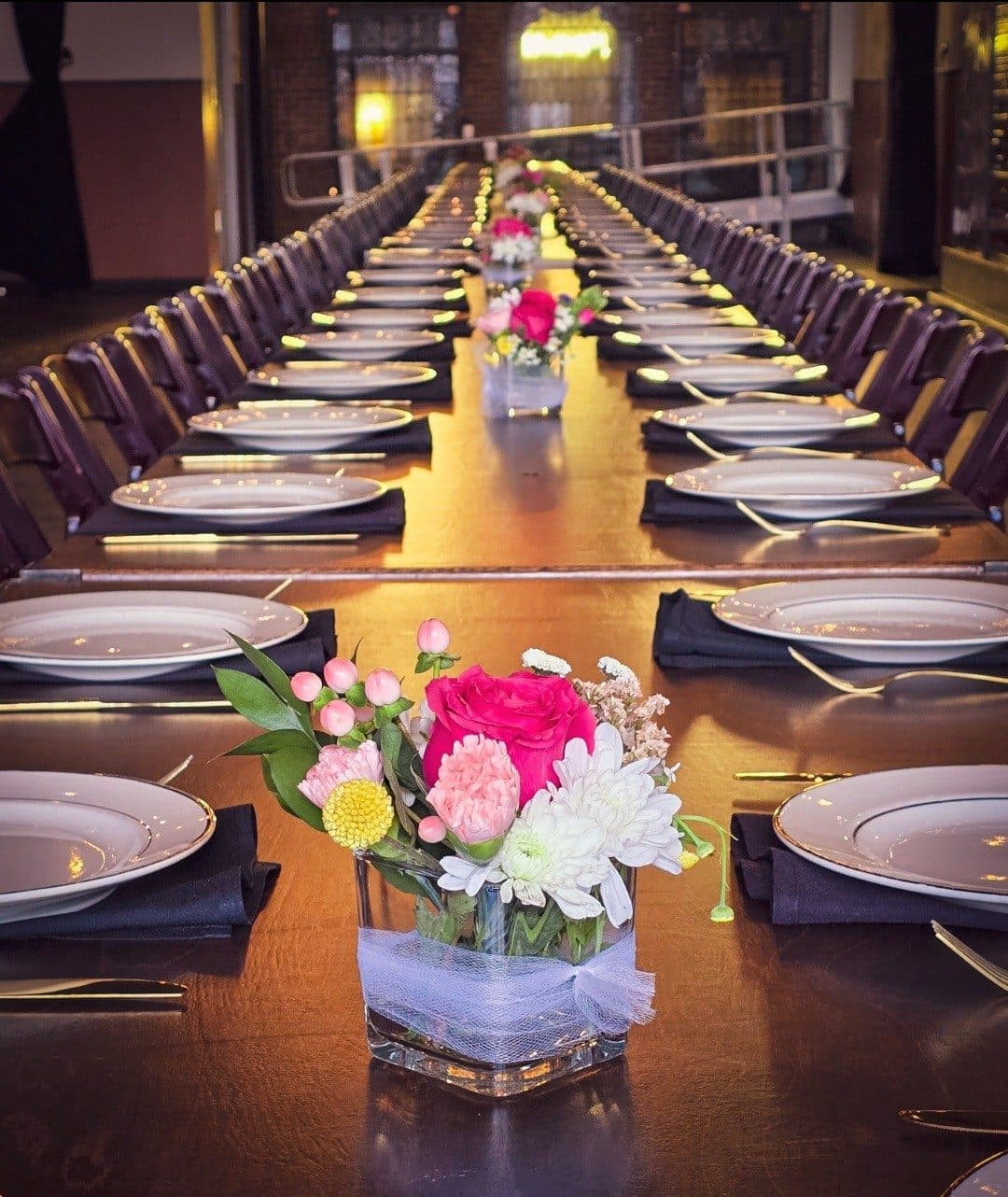 Reception table with pink and white floral centerpieces and place settings